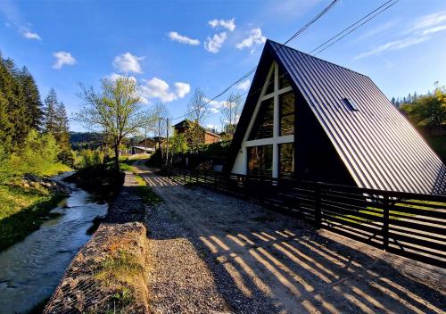 a barn with a fence next to a river at Gloriosa Chalet in Voronet