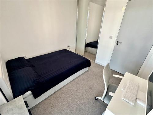 a small room with a bed and a desk and a computer at City Centre Penthouse Bedroom in Birmingham
