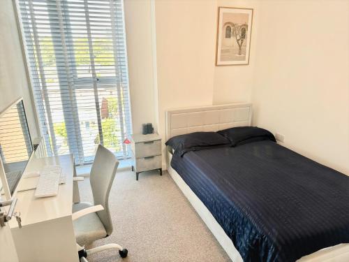 a bedroom with a bed and a desk with a computer at City Centre Penthouse Bedroom in Birmingham