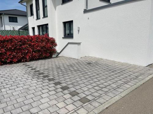 a brick parking lot next to a white building at Ferienwohnung In Ruhiger Lage In Seenähe in Oberteuringen