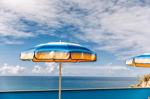 two beach umbrellas sitting on a beach near the ocean at Hotel Cava Dell'Isola in Ischia