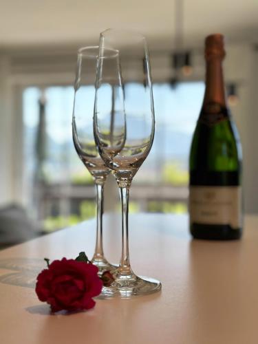 two wine glasses sitting on a table next to a bottle of wine at AlpenLodge Allgäu 5* in Ofterschwang