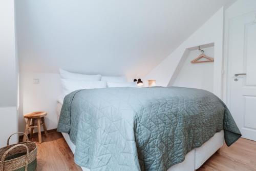 a white bedroom with a bed with a green comforter at Spreewaldhaus Am Landgut Der Stall in Markische Heide
