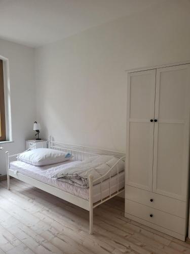 a white bedroom with a bed and a cabinet at Lilienstein in Königstein an der Elbe