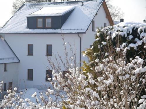 a white house with snow on the roof at Gästehaus Siebert in Bad Brambach
