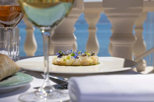 a plate of food on a table with a glass of wine at Hôtel Les Mouettes - Teritoria in Ajaccio