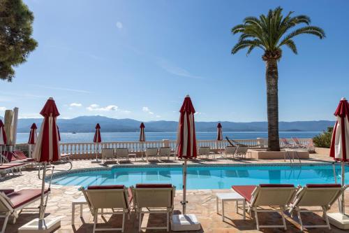 a swimming pool with chairs and a palm tree at Hôtel Les Mouettes - Teritoria in Ajaccio