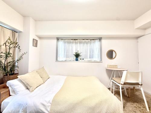 a white bedroom with a bed and a table at MIKASA guesthouse2 in Tokyo