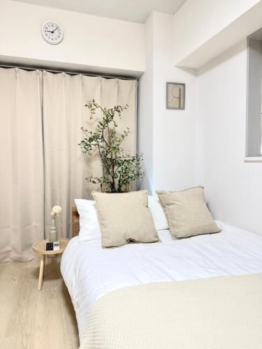 a bedroom with a white bed and a clock on the wall at MIKASA guesthouse2 in Tokyo