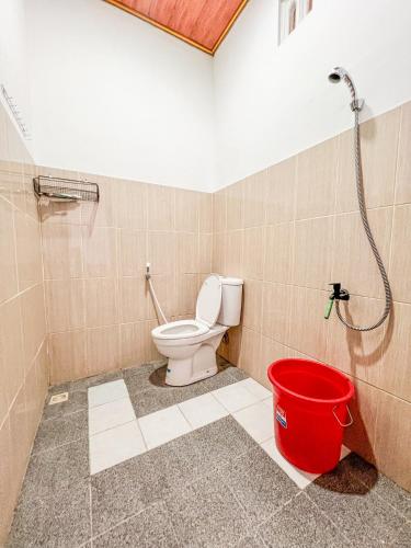 a bathroom with a toilet and a red bucket at Homestay Abbasy Prambanan in Prambanan