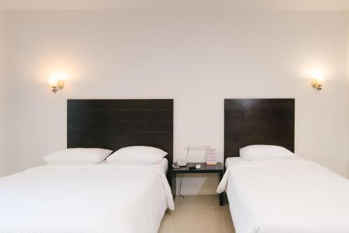 two beds in a room with white sheets at Wilacha Chiang Rai in Chiang Rai
