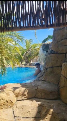 a person sitting in a swimming pool in a resort at Chalés Refúgio Fortim in Fortim