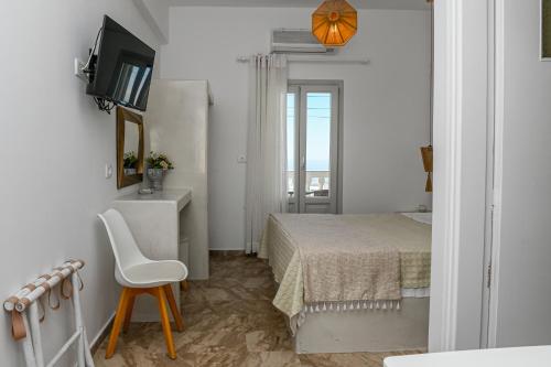 a small white bedroom with a bed and a chair at Vinas Place City Center in Fira