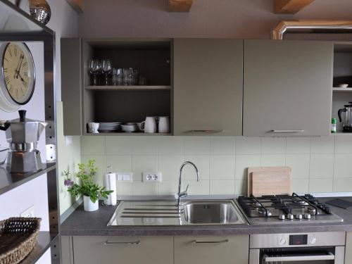 a kitchen with a sink and a clock on the wall at Sole e Fiori di Erik Gaebler in Paschero