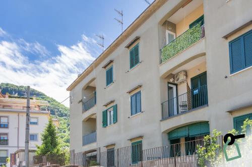 a tall white building with green shutters on it at HOTIDAY Room Collection - Byò Home in Sorrento