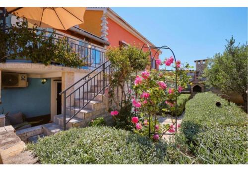 a house with a staircase and pink flowers in a yard at ILOVIK FLOWER in Ilovik