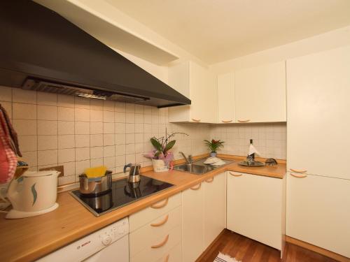 a kitchen with white cabinets and a black hood at Residence Salvan in Corvara in Badia