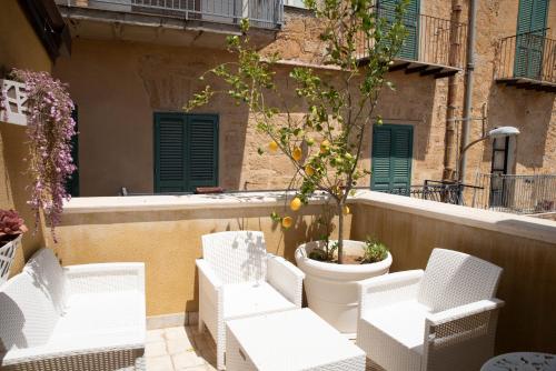 a group of white chairs and a tree on a balcony at La Dolce Vita rooms & suite in Agrigento
