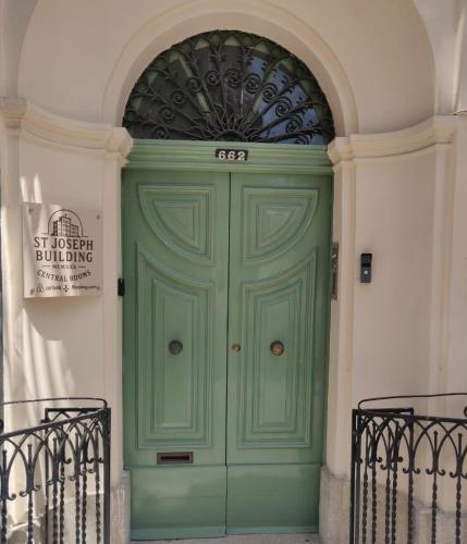 a green door in a building with a sign above it at St Joseph Building Central Rooms in Hamrun