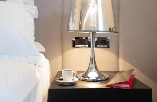 a nightstand with a table with two cups and a lamp at Sofitel Athens Airport in Athens