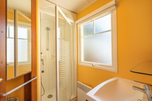 La salle de bains est pourvue d'un lavabo, d'une douche et d'une fenêtre. dans l'établissement Mh 25 Les Genêts Ronce les bains, à La Tremblade