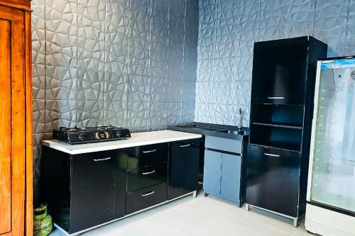 a kitchen with black cabinets and a black refrigerator at Margarita Surf Hostel Canggu in Canggu