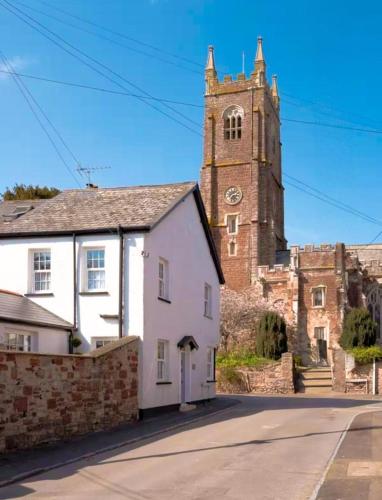 a church with a clock tower and a white house at Charming Kenton Cottage in Kenton