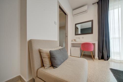 a living room with a couch and a pink chair at CARO Boutique Guest House in San Ġwann