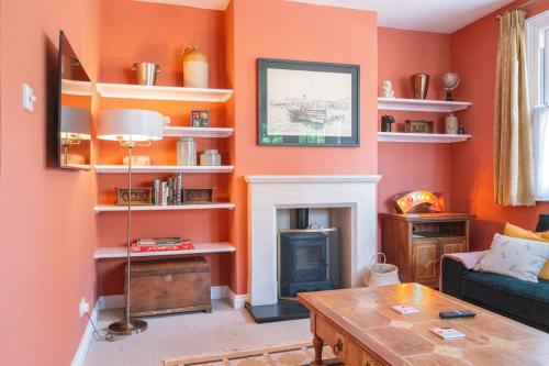 a living room with orange walls and a fireplace at Charming Kenton Cottage in Kenton