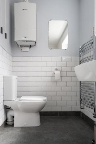 a white bathroom with a toilet and a sink at Charming Kenton Cottage in Kenton