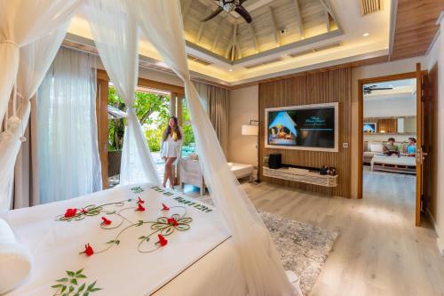 a woman standing in a bedroom with a bed at Lily Beach Resort and Spa - All Inclusive in Dhangethi