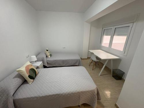 a bedroom with two beds and a desk and a window at apartamento san urbano in Almería