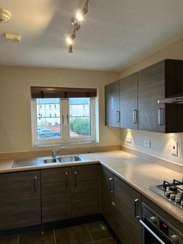 a kitchen with wooden cabinets and a sink and a window at Wonderful two bedroom house in Bicester in Chesterton