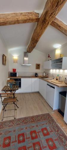 a kitchen with white cabinets and a table and chairs at Bel appartement domaine viticole in Brignoles