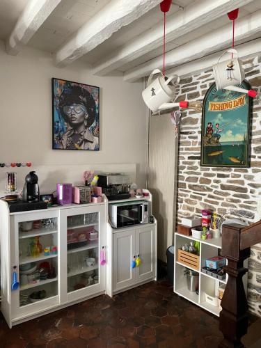 une cuisine avec des placards blancs et un mur en briques dans l'établissement Suite Retour en Enfance, à Dol-de-Bretagne