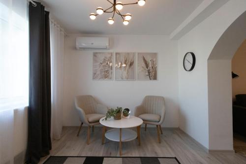 a table and chairs in a living room with a chandelier at Focalize Apartament in Buzau