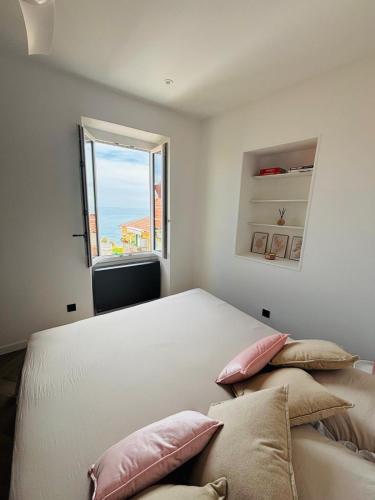 une chambre avec un lit avec des oreillers et une fenêtre dans l'établissement T4 Old Town Menton - Mer-Cœur de la Piétonne, à Menton