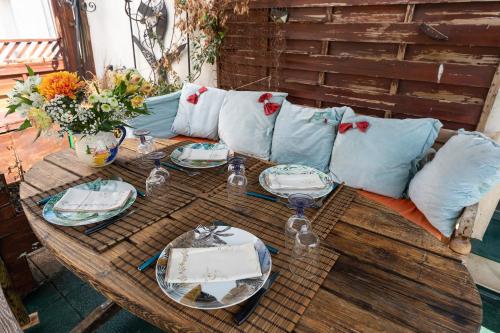 a wooden table with plates and pillows on a couch at Ganges - Appt climatisé avec jacuzzi in Ganges