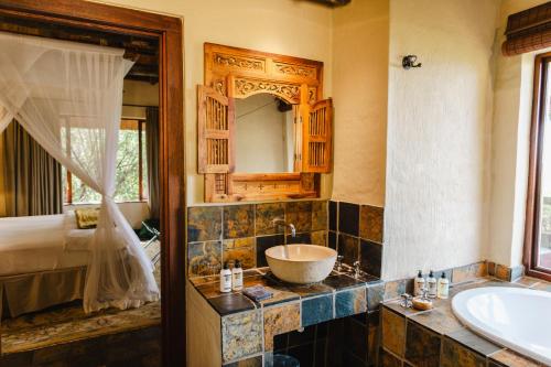 a bathroom with a sink and a tub and a mirror at Hitgeheim Country Lodge in Addo