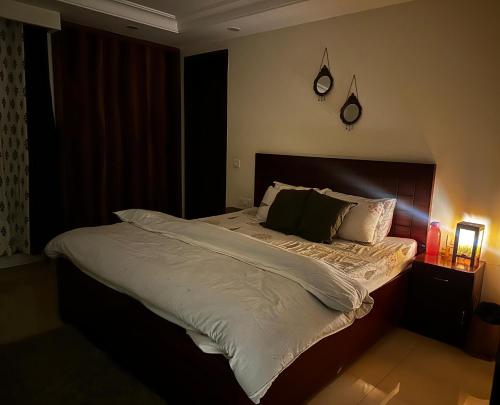 um quarto com uma cama grande com lençóis e travesseiros brancos em Green & Ivory Homestay em Gurgaon