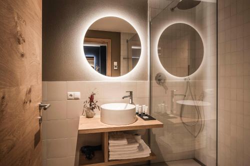 a bathroom with a sink and a shower with a mirror at The Post Mountain Residence in Dobbiaco
