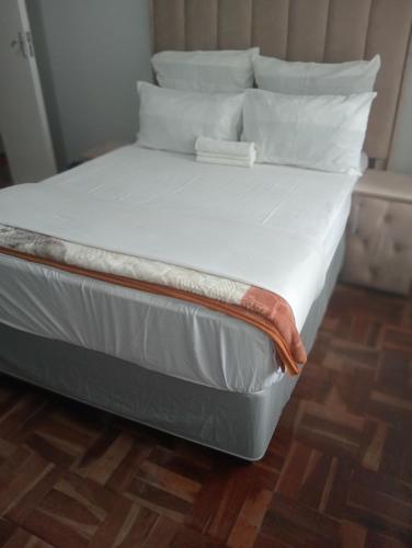 a large bed with white sheets and pillows at Moonlight Guesthouse - Boksburg in Boksburg
