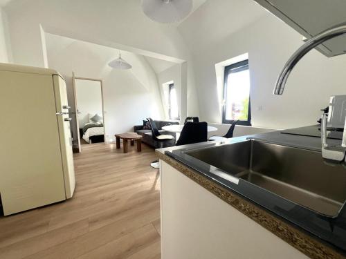 une cuisine avec un évier et un salon dans l'établissement Appartement le Vintage, à deux pas du Port, au Tréport