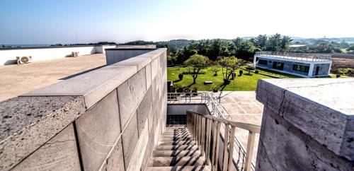 a building with a concrete wall and a yard at Bada Maru Pension in Seogwipo