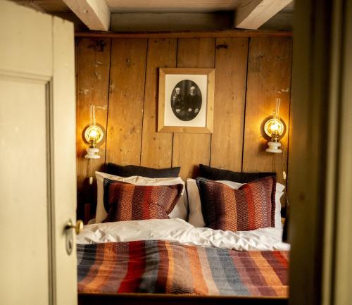 a bedroom with a bed with a wooden wall at Per Amundsagården in Røros