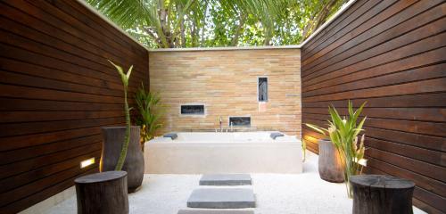 a bathroom with a tub and two potted plants at Lily Beach Resort and Spa - All Inclusive in Dhangethi
