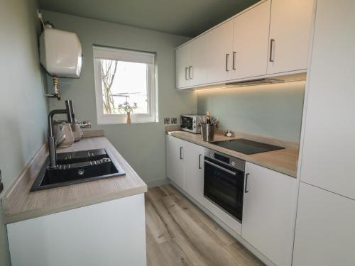 a kitchen with white cabinets and a sink at Number 2 Dome in Doirí Beaga