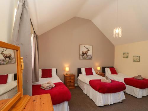 a room with three beds with red pillows in it at Partridge Cottage in Filey