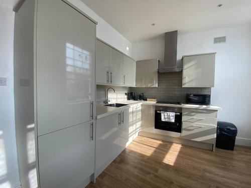 a kitchen with white cabinets and a stove at The Essex Atelier Studio Flat 2 in Chelmsford
