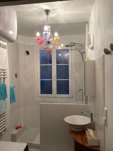une salle de bain blanche avec un lavabo et une fenêtre dans l'établissement Chambres d'hôtes La Maison Hippolyte, à Paris